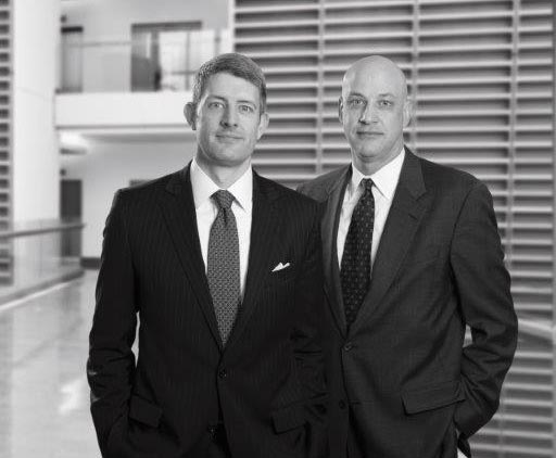 John Abell and Ray Hamm standing in an atrium in front of tall louvred walls.